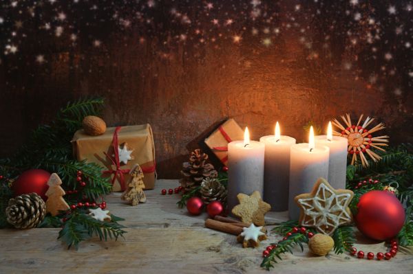 Vierter Advent, vier Kerzen werden angezündet, Weihnachtsdekoration und Geschenke auf rustikalen Holzdielen vor dunkelbraunem Hintergrund mit Kopierraum, ausgewähltem Fokus, schmaler Schärfentiefe
