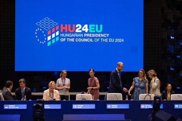 9 Personen sind im EU-Parlament, im Hintergrund ist eine Leinwand zu sehen