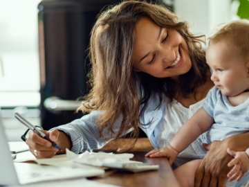 Eine im Home Office arbeitenden junge Frau mit ihrem Baby 