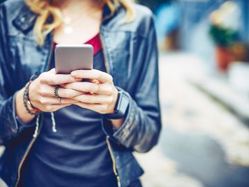 Frau hält Smartphone vor sich im Freien